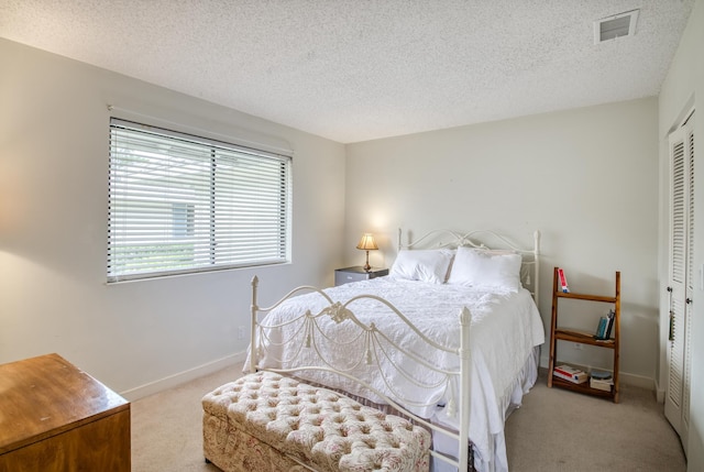 bedroom featuring a textured ceiling, light carpet, and a closet