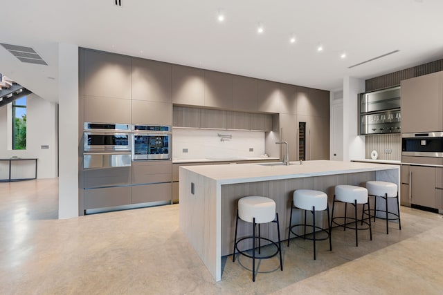 kitchen with decorative backsplash, a kitchen bar, gray cabinets, and a spacious island