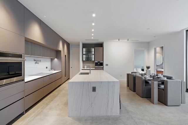 kitchen with backsplash, oven, a spacious island, sink, and black electric cooktop