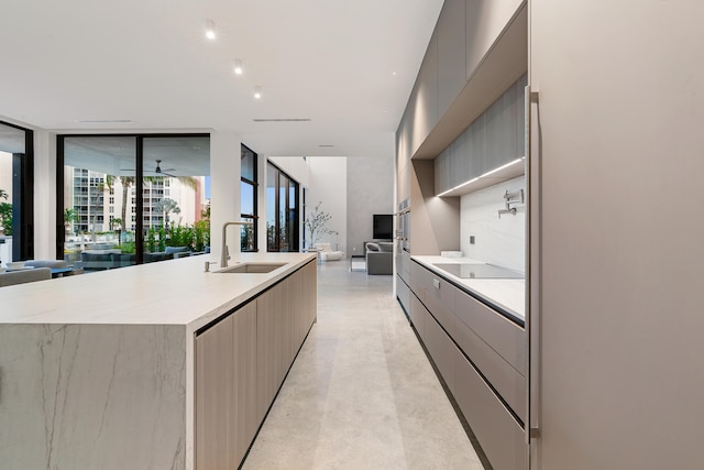 kitchen featuring gray cabinetry, light brown cabinets, a spacious island, sink, and a wall of windows