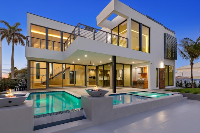 back house at dusk with a balcony, an outdoor fire pit, and a patio