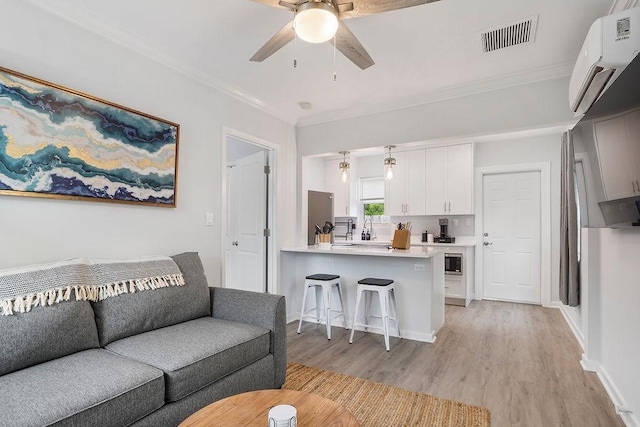 living room featuring ceiling fan, ornamental molding, sink, and light hardwood / wood-style flooring