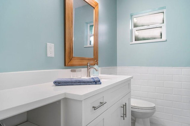 bathroom with vanity, toilet, and tile walls