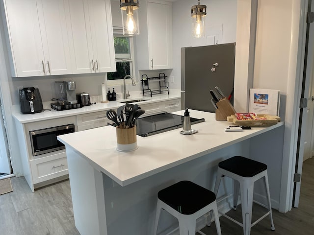 kitchen with appliances with stainless steel finishes, sink, hanging light fixtures, and white cabinets