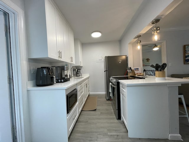 kitchen featuring pendant lighting, white cabinetry, sink, kitchen peninsula, and stainless steel appliances