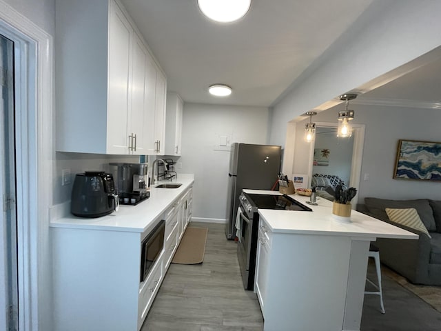 kitchen with sink, white cabinetry, decorative light fixtures, appliances with stainless steel finishes, and a kitchen breakfast bar