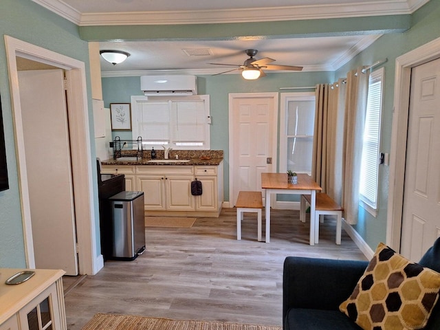 kitchen featuring crown molding, sink, a wall mounted AC, and light hardwood / wood-style flooring