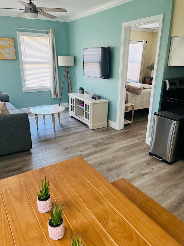 living room featuring a healthy amount of sunlight, hardwood / wood-style floors, ornamental molding, and ceiling fan