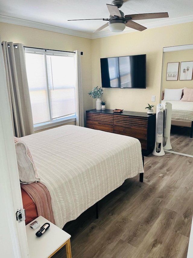 bedroom featuring hardwood / wood-style floors, ornamental molding, and ceiling fan