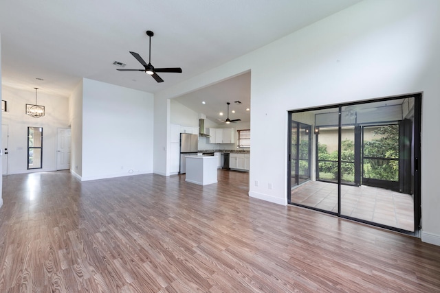 2843 SW Mariposa Cir, Palm City, FL 34990 - unfurnished living room featuring a high ceiling, wood finished floors, a ceiling fan, and baseboards