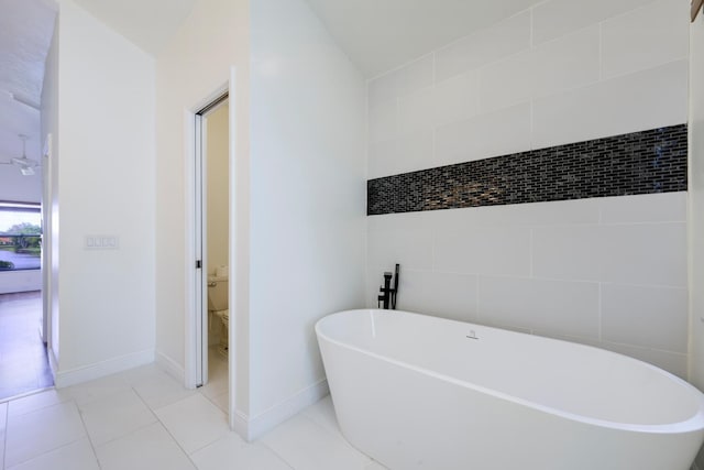 2843 SW Mariposa Cir, Palm City, FL 34990 - bathroom featuring a soaking tub, toilet, tile patterned floors, and tile walls