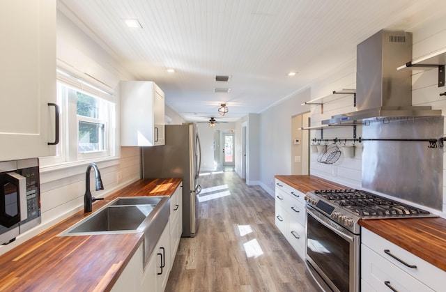 kitchen featuring white cabinets, wood counters, stainless steel appliances, and tasteful backsplash