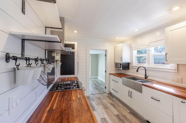 kitchen featuring wooden counters, white cabinets, light hardwood / wood-style flooring, and sink