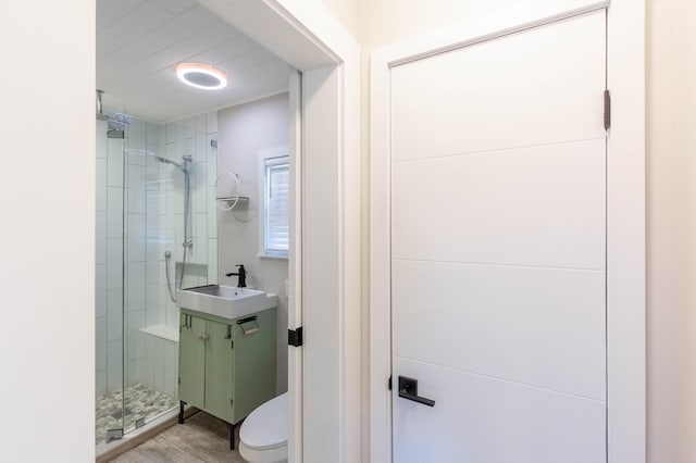 bathroom featuring hardwood / wood-style flooring, toilet, a shower with shower door, and sink