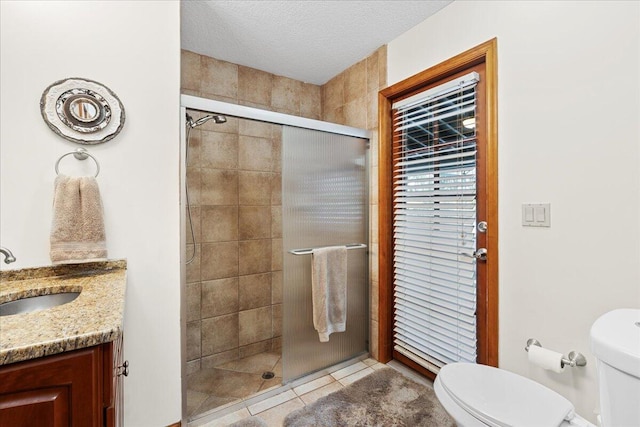 bathroom with vanity, tile patterned flooring, toilet, a textured ceiling, and an enclosed shower