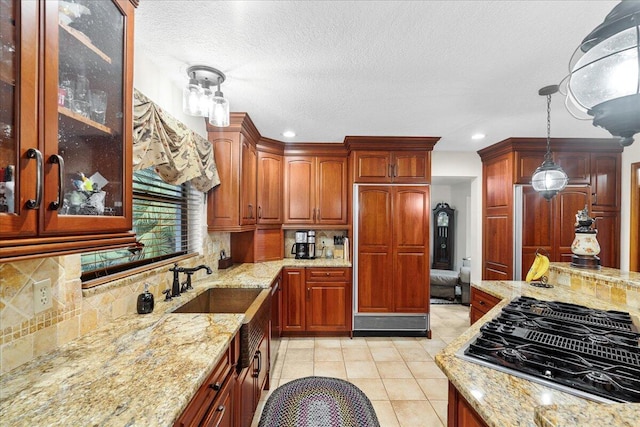 kitchen with light stone counters, backsplash, black gas stovetop, pendant lighting, and light tile patterned flooring