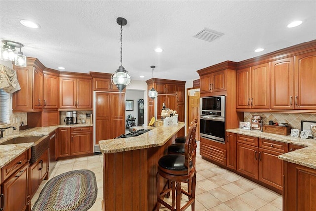 kitchen featuring backsplash, light stone counters, sink, and pendant lighting