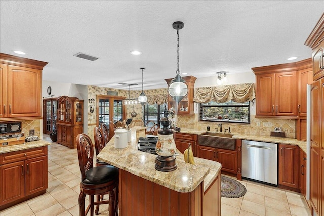 kitchen with a kitchen breakfast bar, sink, decorative light fixtures, dishwasher, and a center island