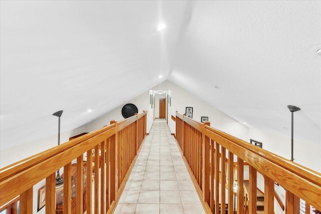 corridor with light tile patterned floors and vaulted ceiling