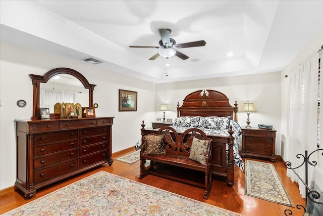 bedroom featuring hardwood / wood-style floors, a tray ceiling, and ceiling fan