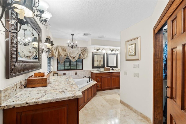 bathroom featuring vanity, an inviting chandelier, a textured ceiling, and a tub