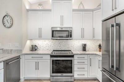 kitchen with light stone countertops, white cabinetry, and stainless steel appliances