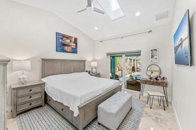 bedroom featuring access to outside, lofted ceiling with skylight, and ceiling fan