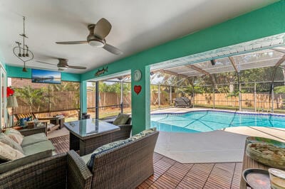 view of swimming pool with outdoor lounge area, a patio, ceiling fan, and a lanai