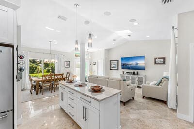 kitchen featuring white cabinets, pendant lighting, vaulted ceiling, and a kitchen island