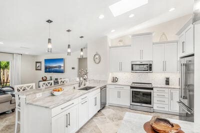 kitchen featuring a breakfast bar area, kitchen peninsula, white cabinetry, and appliances with stainless steel finishes