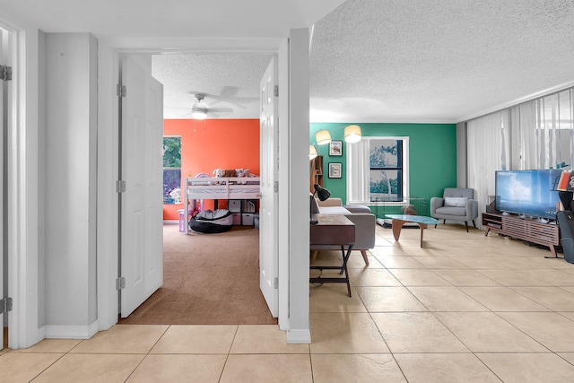 corridor featuring light tile patterned floors, a textured ceiling, and a wealth of natural light