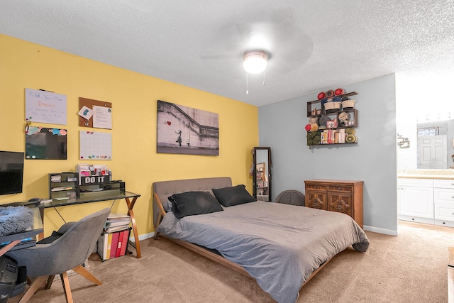 bedroom with a textured ceiling, ensuite bathroom, ceiling fan, and light colored carpet