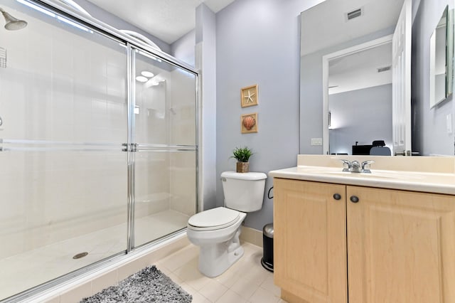 bathroom with tile patterned floors, vanity, a shower with shower door, and toilet