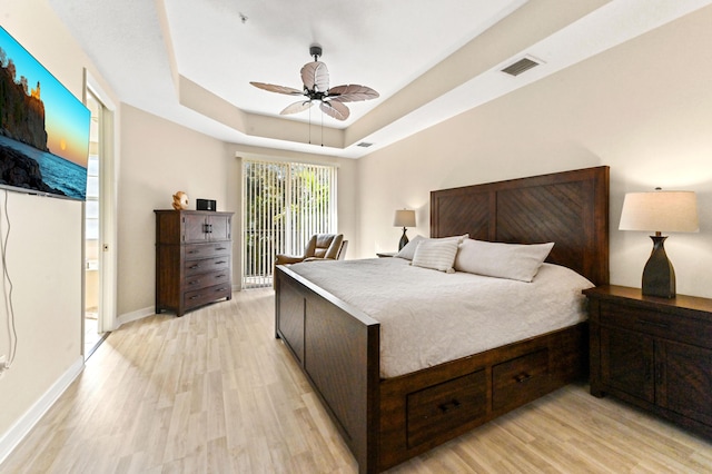 bedroom featuring ceiling fan, light hardwood / wood-style floors, and a raised ceiling