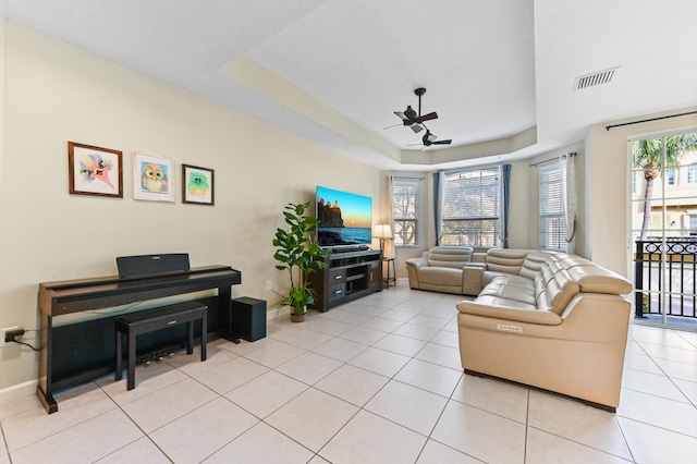 tiled living room featuring a raised ceiling and ceiling fan