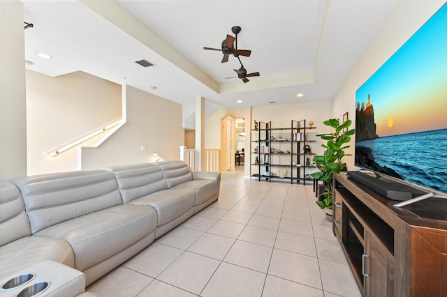 tiled living room featuring ceiling fan and a tray ceiling