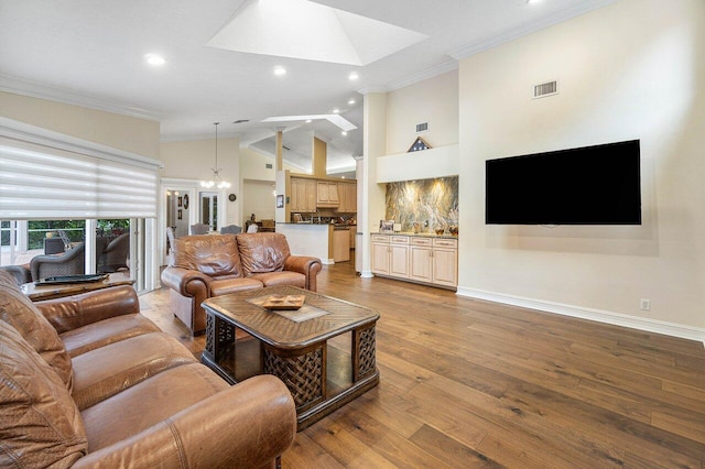 living room featuring high vaulted ceiling, an inviting chandelier, crown molding, a skylight, and light wood-type flooring