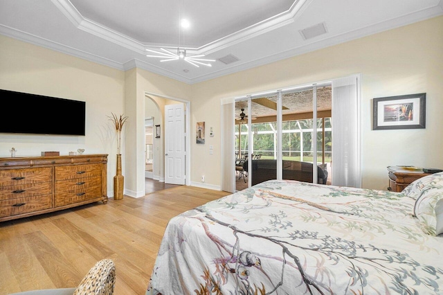 bedroom with ornamental molding, access to outside, a tray ceiling, and light hardwood / wood-style floors