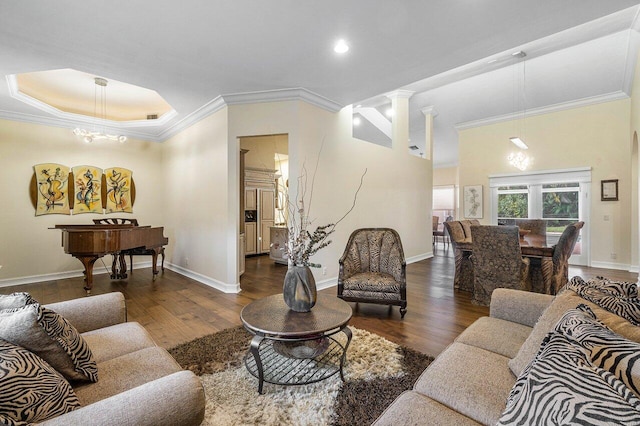 living room featuring a chandelier, decorative columns, crown molding, and dark wood-type flooring