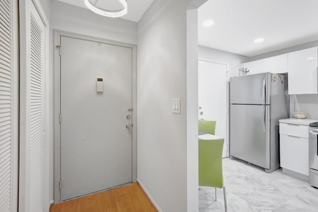 kitchen with white cabinets, electric stove, stainless steel refrigerator, and light hardwood / wood-style flooring