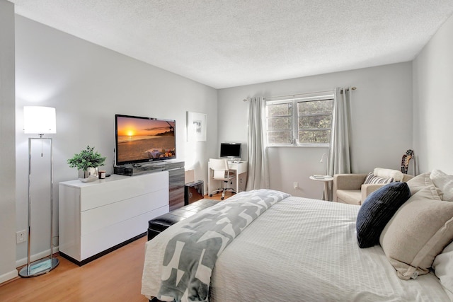 bedroom with a textured ceiling and light hardwood / wood-style flooring