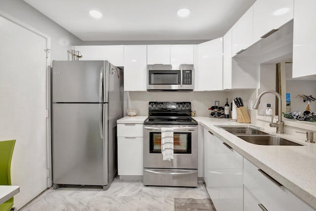 kitchen featuring white cabinetry, sink, stainless steel appliances, and light stone counters