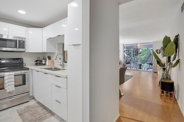 kitchen featuring sink, white cabinets, stainless steel appliances, and light hardwood / wood-style floors