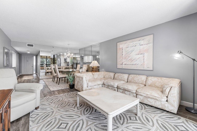 living room featuring a notable chandelier, a textured ceiling, and light hardwood / wood-style flooring