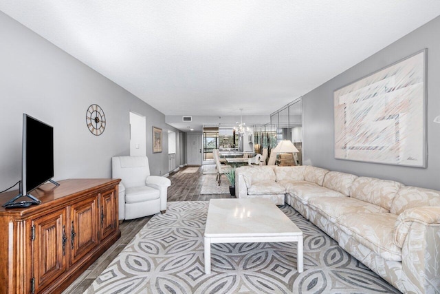 living room with a notable chandelier, wood-type flooring, and a textured ceiling