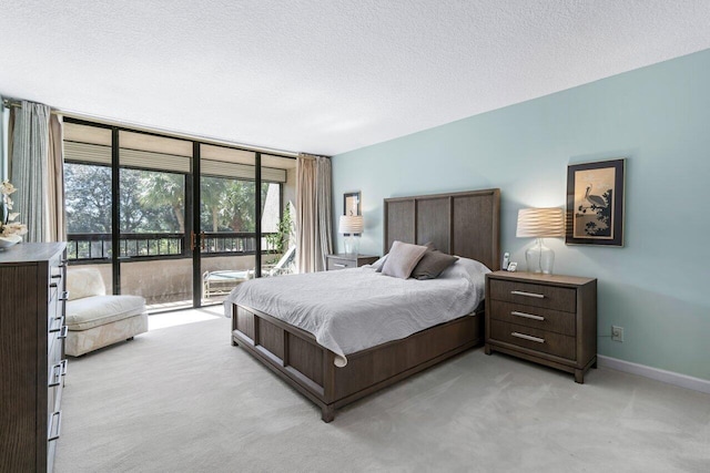 bedroom with access to outside, light colored carpet, a textured ceiling, and a wall of windows