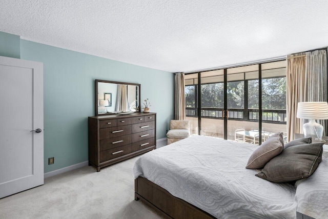 bedroom with access to outside, a textured ceiling, and light colored carpet