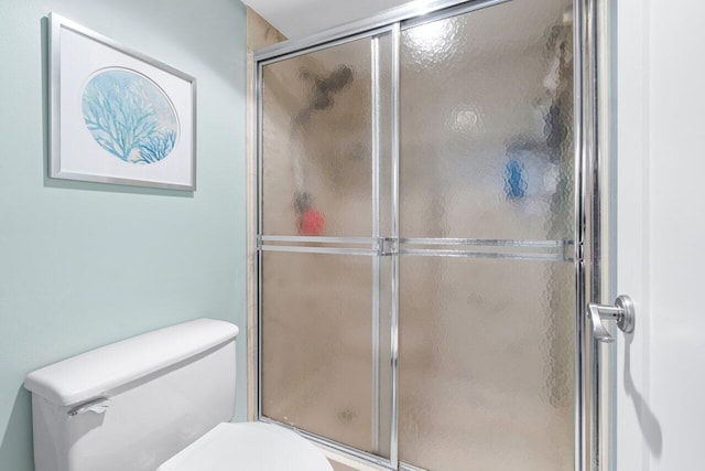 bathroom featuring a shower with shower door and toilet