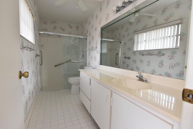 bathroom featuring ceiling fan, tile patterned flooring, toilet, vanity, and a shower with shower door