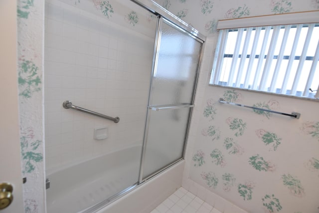 bathroom with combined bath / shower with glass door and tile patterned floors